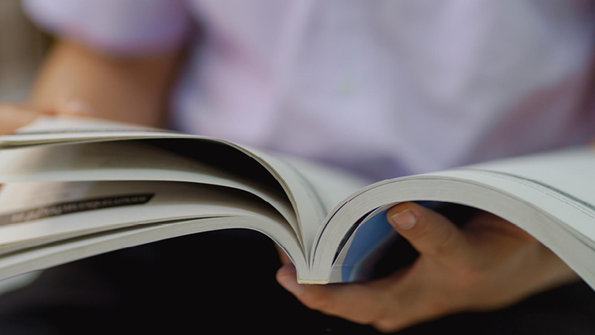 Close-up of hands flipping through a bound report