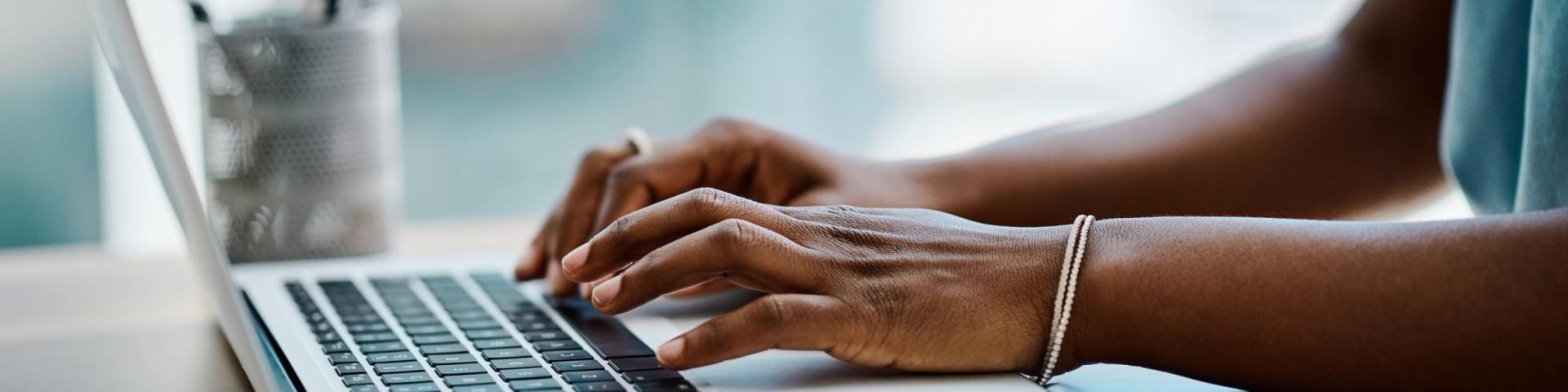 Close up of a business woman's arms typing on a laptop keyboard